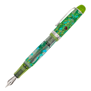 A clear frosted fountain pen with translucent lime green details and silver trim with details of turquoise and green leaves and butterflies, and a red ladybug on the cap. The cap is posted on the barrel and the pen is diagonal on a white background.