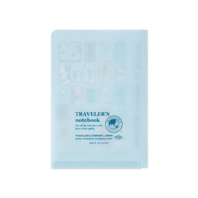 A light blue translucent plastic notebook cover with travel icons and printed blue text reading 'TRAVELER'S notebook' and 'Traveler's Company, Japan' on a white background.
