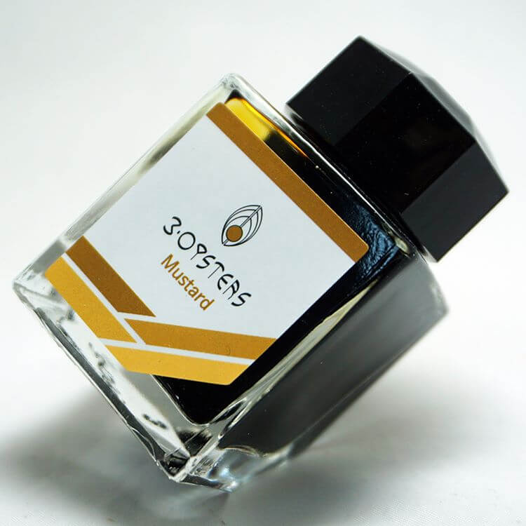 3 Oysters Mustard from the Delicious collection is a medium brown-yellow fountain pen ink with medium shading. It dries in 30 seconds in a medium nib on Rhodia and has a dry flow. The glass bottle has a cut out corner to lean the bottle for a decorative display. 3 Oysters ink is made in Korea.  Pantone color: 1245C