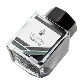3 Oysters Black Moss from the Delicious collection is a dark green-black fountain pen ink with a pop of black sheen in large swabs. It dries in 30 seconds in a medium nib on Rhodia and has an average flow. The glass bottle has a cut out corner to lean the bottle for a decorative display. 3 Oysters ink is made in Korea.